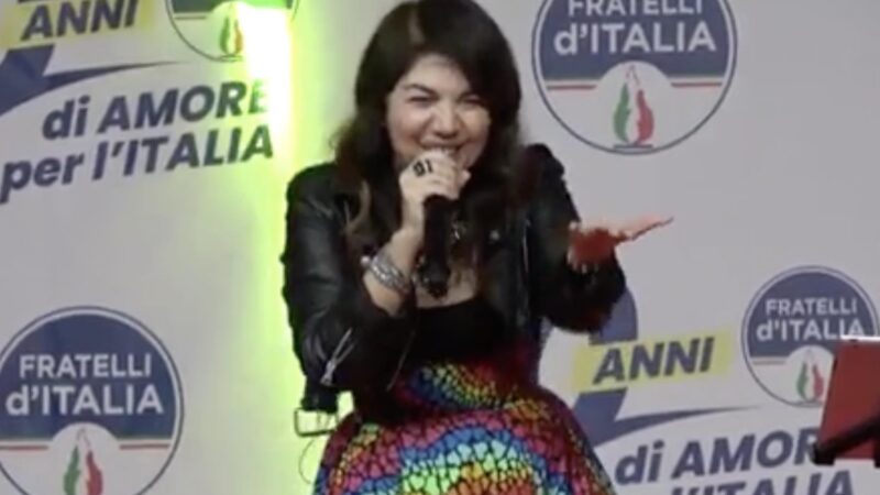 Cristina D’Avena alla festa FdI con gonna arcobaleno canta Lady Oscar: “Inno all’amore universale”